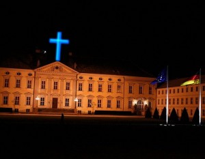 ein blaues Neonkreuz  ziert Schloss Bellevue, Montage: Ulli Schauen